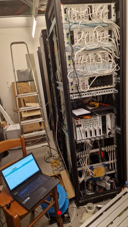 Sala tecnica con rack e centrali Fracarro per distribuzione IPTV e TV-SAT, configurazione in corso tramite laptop